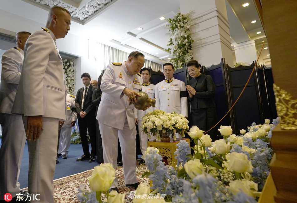 泰国副总理巴维身着白色礼服，神情肃穆地跪坐在悼念席上，双手合十，额头轻触指尖，向这位为泰国赢得国际声誉的亿万富豪致以最后的敬意，周围的烛光在他脸上映出凝重的光影。