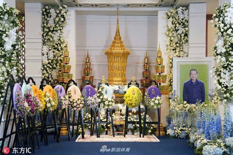 在曼谷Wat Thepsirin寺庙庄严的氛围中，维猜的灵柩被鲜花与王室御赐圣物环绕，金色的寺庙尖顶在夕阳下映照着前来送别的人群，空气中仿佛弥漫着檀香与哀思。