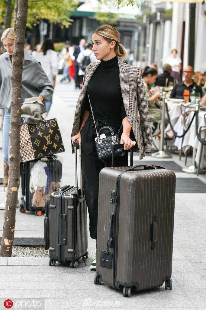 凯瑟琳现身米兰街头，她戴着墨镜，长发披肩，一身休闲装扮难掩超模气质，正费力地拖拽着一个巨大的行李箱，准备开启她的时装周之旅。