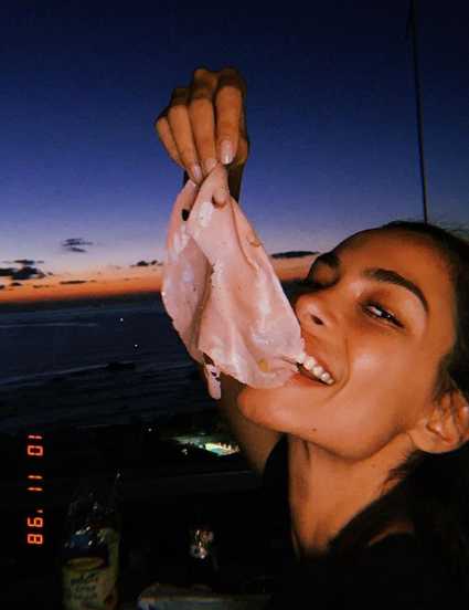 Joana Sanz置身于巴黎的奢华酒店内，一袭白色深V长裙勾勒出曼妙身姿，她侧身而立，神态慵懒，背景的柔和光线为她镀上一层柔光，尽显高贵典雅。