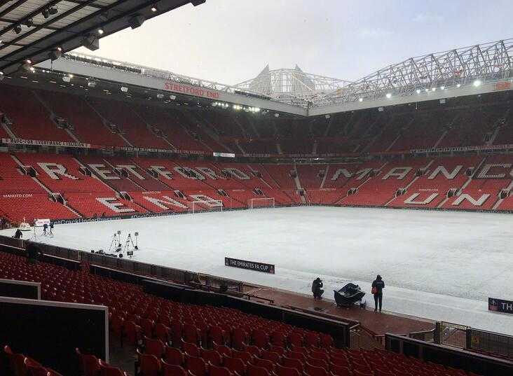 梦剧场的冬日恋歌:老特拉福德雪景中的诗意与荣光 在漫天飞舞的雪花中,曼联的球员们正在场上进行热身,他们呼出的白气与飘落的雪花交织,看台上覆盖着薄雪,整个场景充满了一种冷峻而热烈的备战氛围。