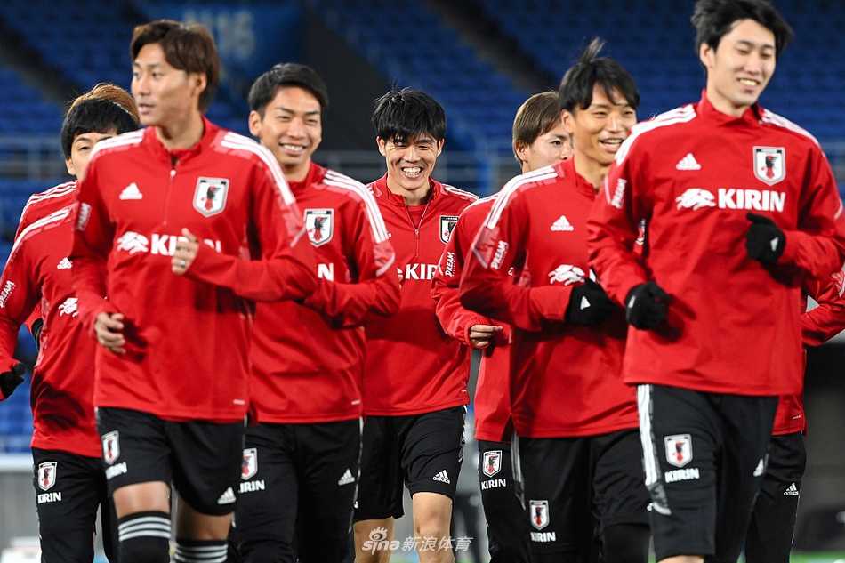 横滨黄昏的蓝武士:森保一军团为宿敌之战磨刀霍霍 横滨晚霞中,日本队球员们在进行热身,拉伸的身影与绿茵场构成一幅充满动感的备战画卷