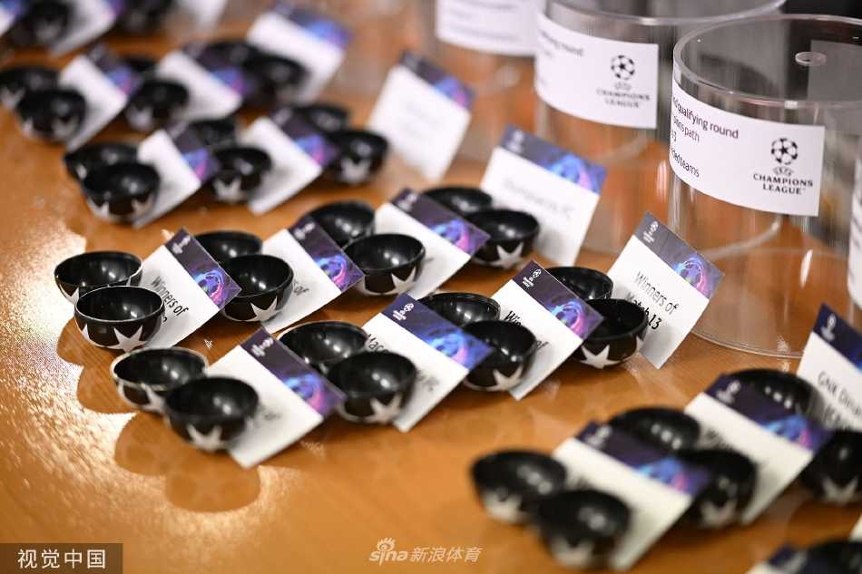 抽签嘉宾面带微笑凝视着手中的小球，背后大屏幕清晰地展示着即将成形的对阵形势
