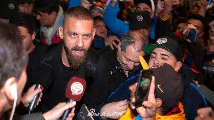 德罗西在新闻发布会上展示博卡青年16号球衣，面前摆满了话筒和聚光灯，他表情坚毅，正式以博卡球员身份与媒体和球迷见面。