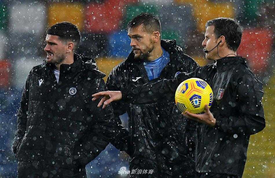 球门前的积水尤为严重，水面几乎快要没过整个球门线，负责场地维护的工作人员身披雨衣，站在水中显得格外渺小和无助。