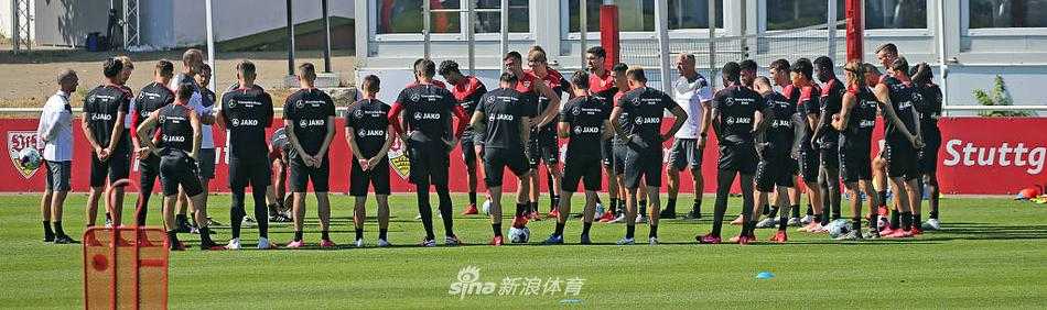 训练间隙，几名斯图加特球员围坐在一起补充水分。他们神情放松，彼此交谈，背景是蓝天白云下的训练基地，构成一幅充满活力的夏日备战画卷。