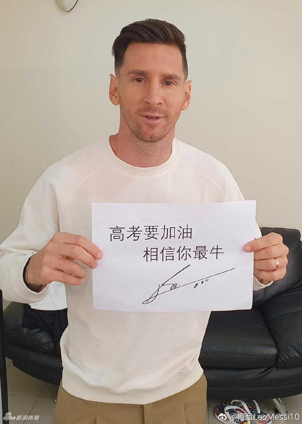 梅西身着休闲装，神情专注地在写有祝福语的纸张下方签下自己名字，每一个笔画都饱含对远方学子的诚挚祝愿。