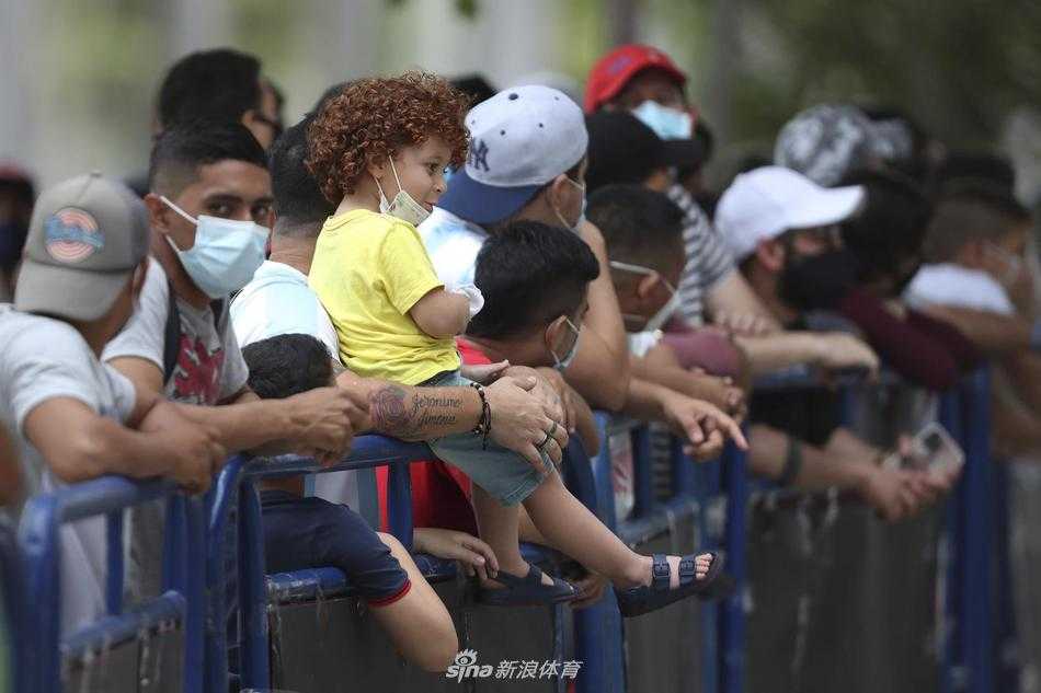 酒店外的街道上人山人海，警察手拉手组成人墙维持秩序，背景里蓝白色的阿根廷旗帜与黄色的哥伦比亚国旗交织在一起，球迷们脸上洋溢着笑容，将这场赛前备战变成了一场属于南美足球的盛大狂欢节。