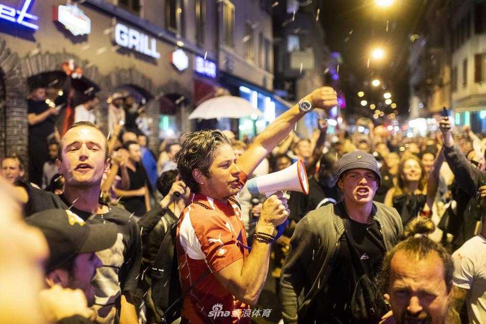 入夜后的苏黎世街头霓虹灯闪烁，密集的人群让有轨电车寸步难行，球迷们爬到路灯杆基座上挥舞旗帜，空气里弥漫着啤酒和狂欢的味道，仿佛整个城市都在随着胜利的节奏摇摆。