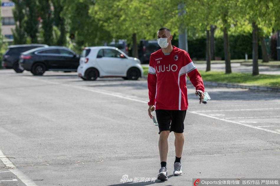 在空旷的训练场上，一名博洛尼亚球员独自带球前进，脸上严实地戴着防护口罩，绿色的草地与冷清的看台形成鲜明对比，仿佛在诉说这个特殊时期的足球故事。