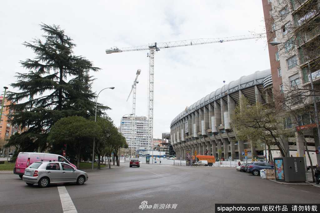伯纳乌球场外围的通道空荡而静谧，阳光透过建筑结构投下长长的光影，昔日球迷们在此驻足拍照、流连忘返的喧嚣场景已不复存在，只留下铁栏杆和紧闭的门窗陪伴着这座孤独的足球圣殿。
