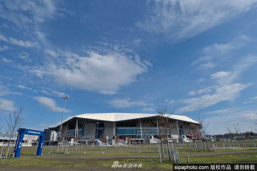 空旷的里昂奥林匹克公园球场内，阳光洒在无人的座位上，看台上原本应挥舞着围巾的球迷消失了，只剩下孤零零的座椅和巨大的电子广告牌，诉说着疫情下的寂静。