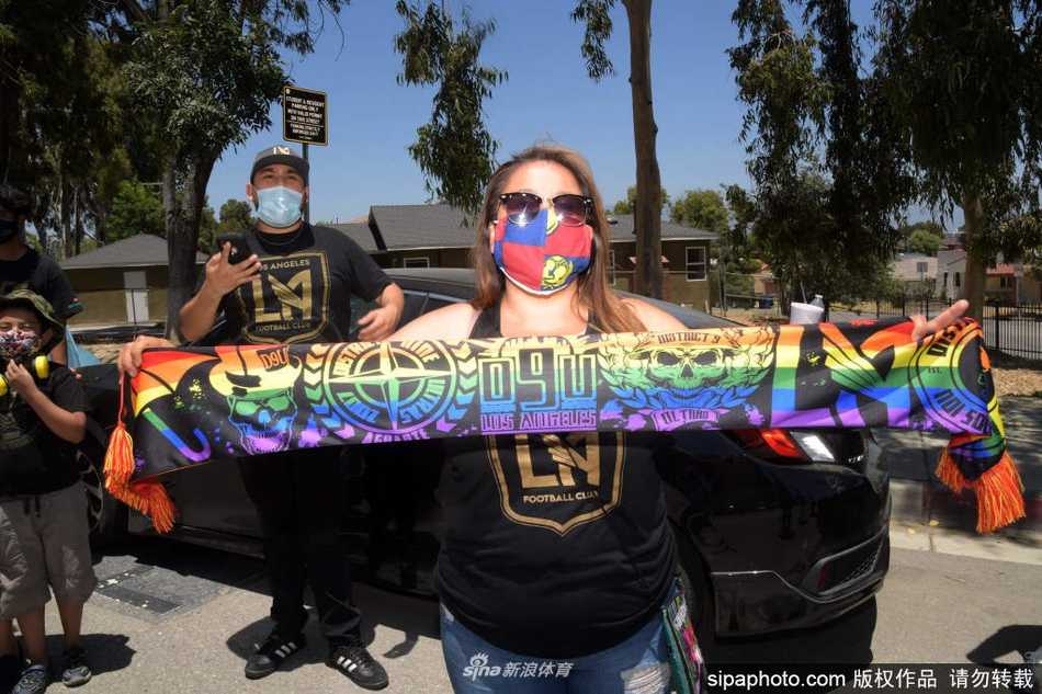 身穿黑色LAFC球衣的狂热球迷们，在街边护栏后高高扬起手臂，用震耳欲聋的呐喊和巨大的队旗，迎接载着英雄们归来的球队大巴。