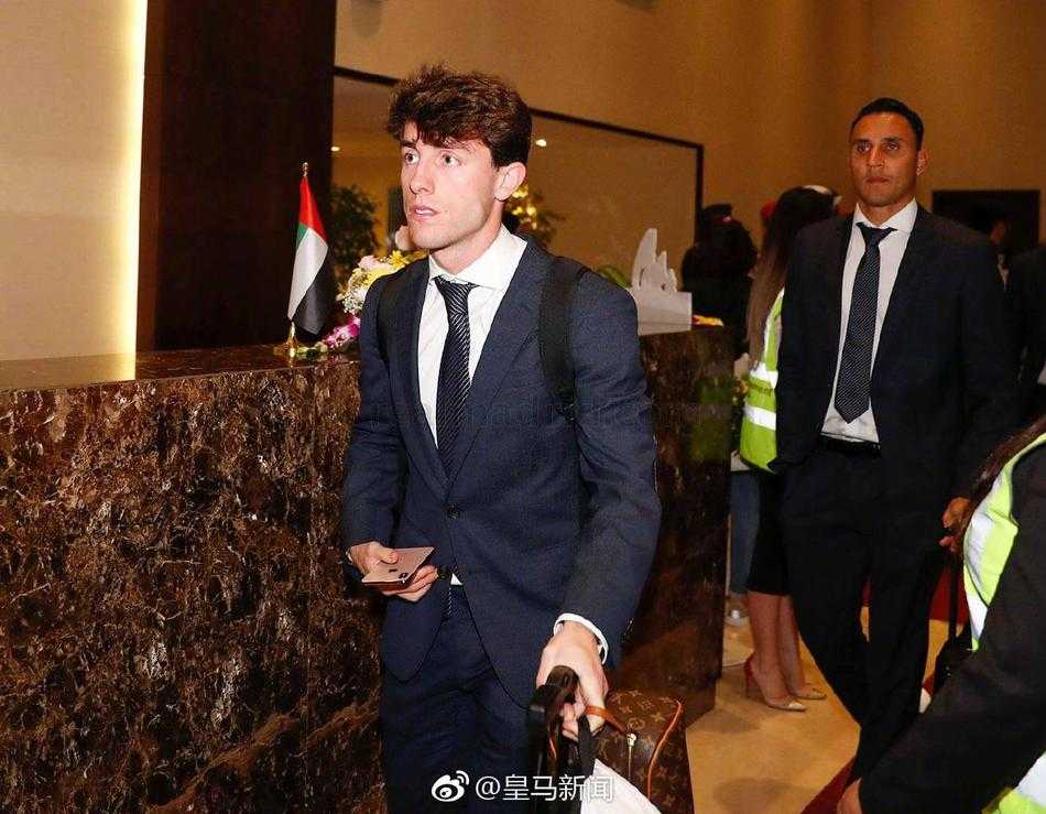 皇马巨星贝尔面带微笑地蹲下身为热情的当地小球迷在纪念品上签名，场边的长枪短炮记录下了这温情一幕