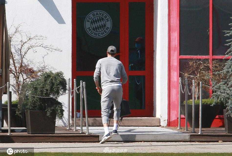 镜头拉远，莱万独自一人走向训练中心的建筑入口，空旷的广场映衬出他略显孤寂的背影。阳光斜照，却难掩他步伐的沉重，这张照片定格了他告别队友、开启漫长康复之路的起点。