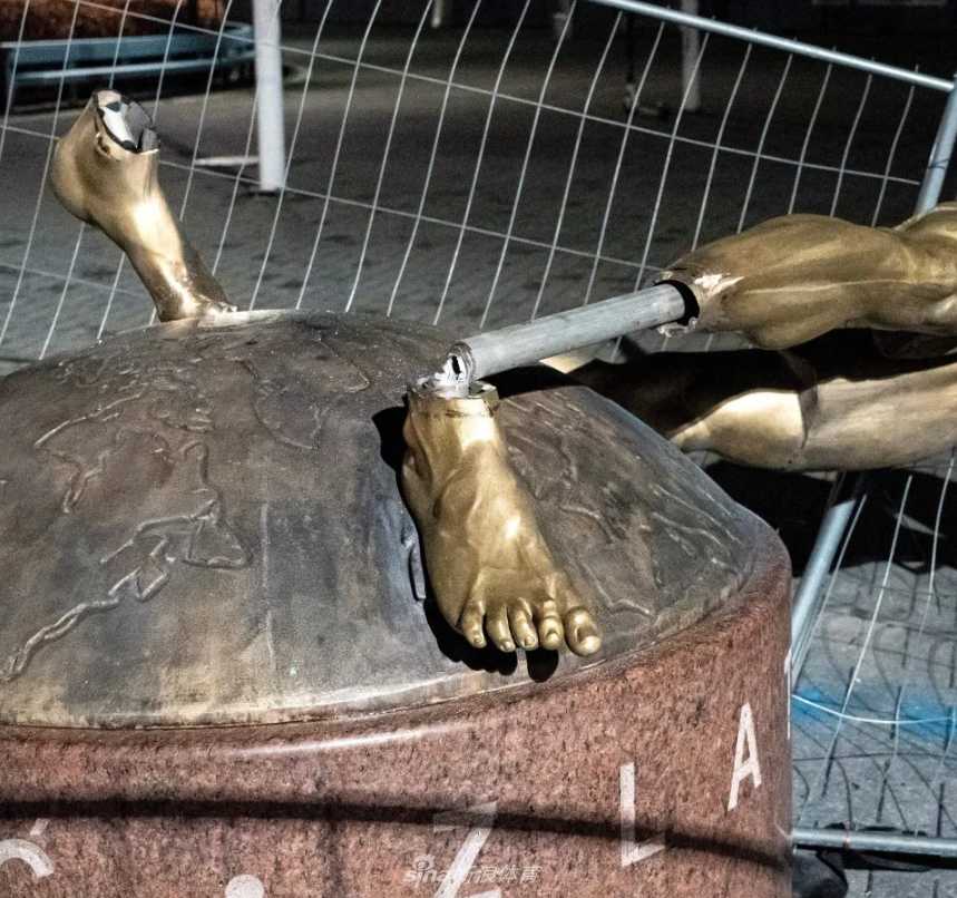 近距离特写显示，雕像的脚踝处已被锯断，裸露的金属骨架与倾倒的黑色身躯，充满悲剧色彩。