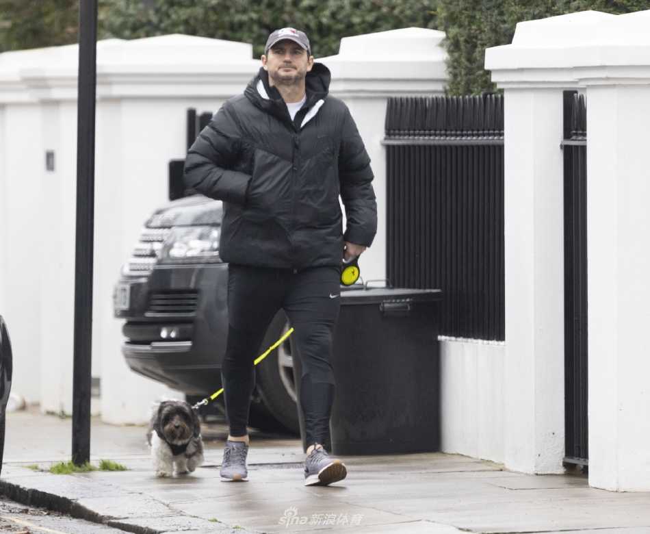 兰帕德的爱犬兴奋地小跑在前方，他微微俯身，目光温柔地追随着宠物的活泼身影，展现出铁汉柔情的一面。