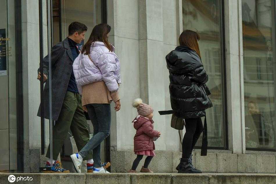 莱万一家在户外行走的动态瞬间，莱万肩扛小女儿，大女儿克拉拉步伐轻快地走在前面，安娜跟在身后。一家人的背影融入冬日街景，画面充满生活气息与流动的幸福感。