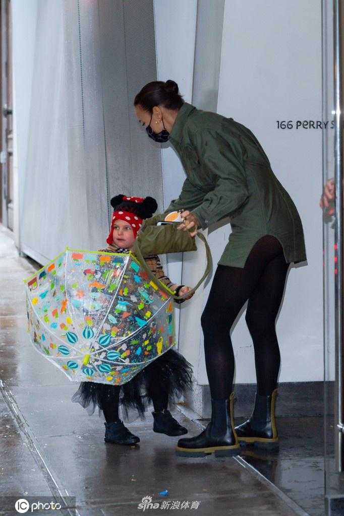 伊莉娜一手提着物品，一手紧紧牵着女儿莉亚。莉亚的小手被妈妈的大手包裹着，安全感十足，她迈着轻快的步子，仿佛在进行一场秋日散步。