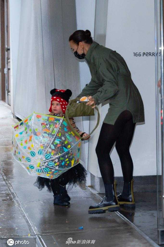 当天外出的完整画面，伊莉娜和女儿莉亚一前一后走在纽约的人行道上。小莉亚手中的花伞在秋日的映衬下格外显眼，母女俩的背影构成了一道温馨而美丽的风景线。