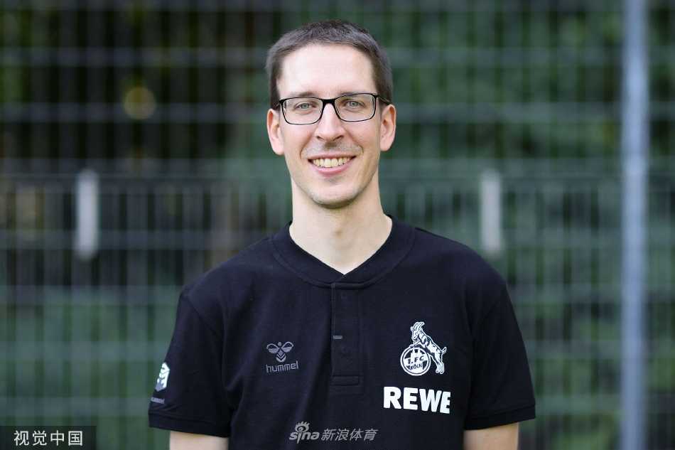 两位科隆后卫并肩而立相视而笑，默契互动捕捉了更衣室内团结友爱的温馨瞬间