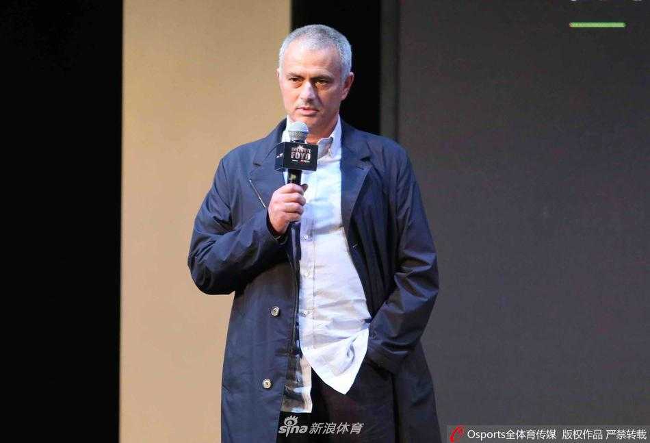 身穿运动装的穆里尼奥手提多袋物资，在社区的绿篱旁与工作人员核对配送清单，神情专注而认真