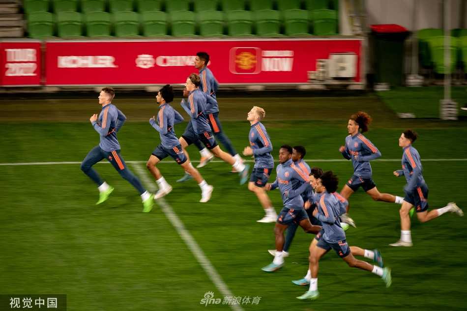 曼联球员在绿茵场上进行高速折返跑训练，身影在炙热阳光下拉长，汗水挥洒，尽显职业球员的刻苦与拼搏。