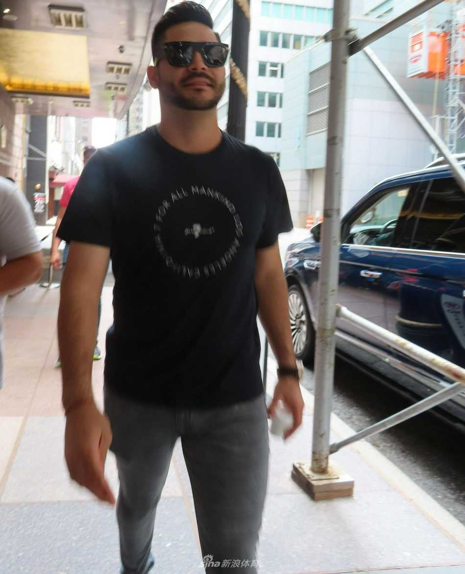 马丁-佩雷斯漫步在纽约繁忙的街头，他身穿合身的黑色T恤，搭配深色牛仔裤，脸上那副墨镜在午后的阳光下反射出城市的光影，整个人显得既低调又星味十足，仿佛一部好莱坞电影中的男主角。