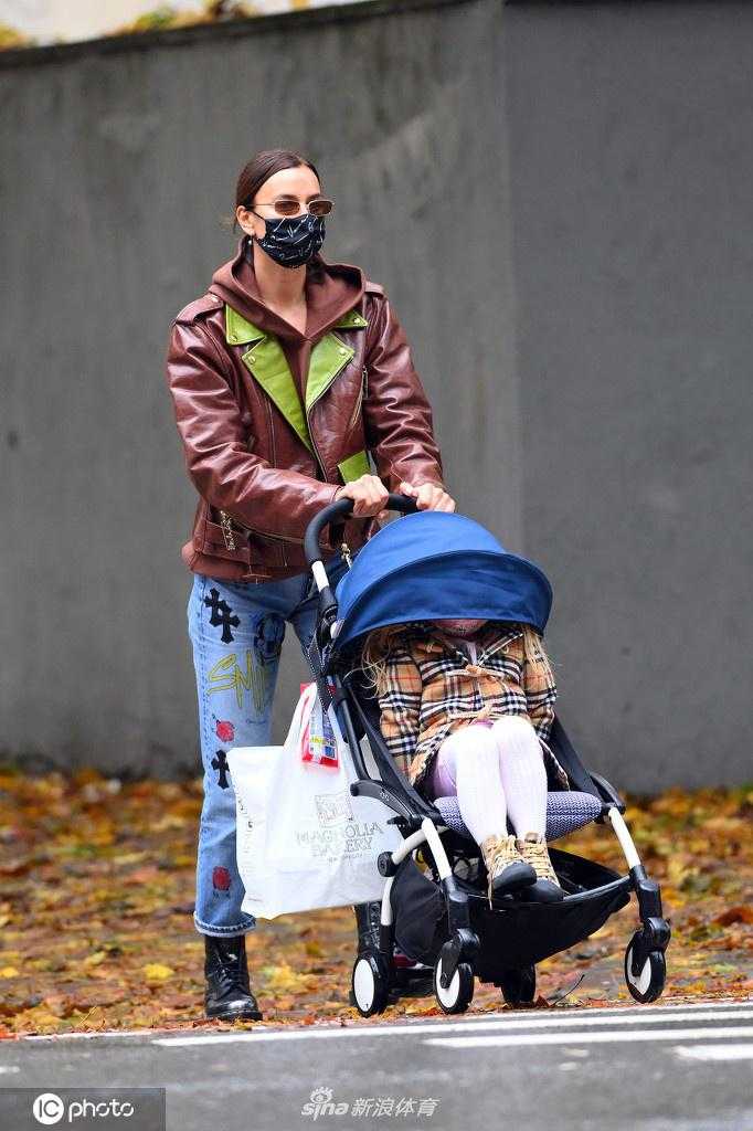 伊莲娜推着婴儿车走在斑马线上，她侧脸看向镜头外的女儿，即便面部被遮挡仍能感受到她时刻关注着孩子的一举一动