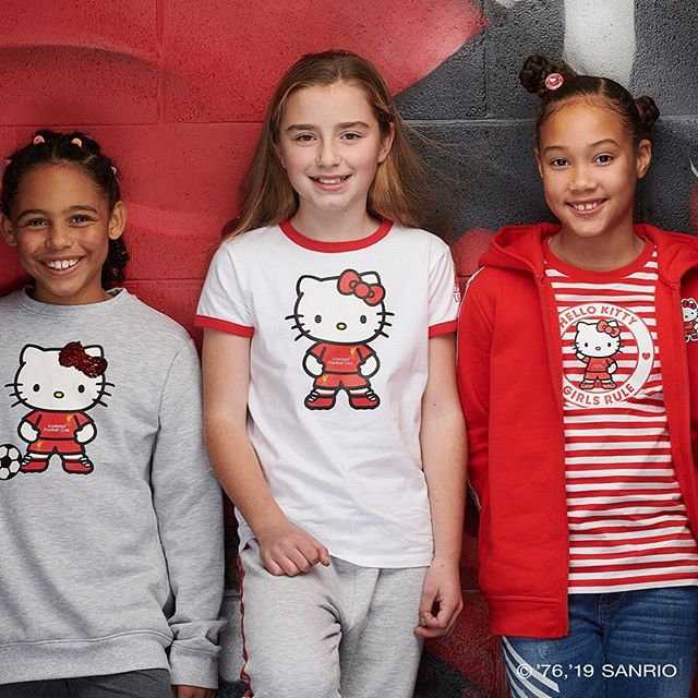 一系列联名产品琳琅满目，包括印有Hello Kitty形象的利物浦球衣、围巾、帽子以及可爱的毛绒玩偶，玩偶中的Kitty还俏皮地踢着一个小足球。