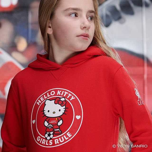 身披利物浦红色战袍的Hello Kitty，标志性的蝴蝶结换成了球队围巾，正抱着足球在安菲尔德的看台上微笑，萌态可掬又不失球迷的激情。