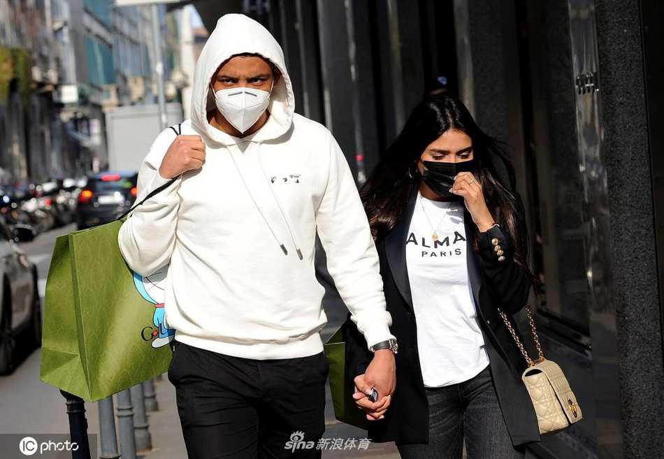 穆列尔一手提着购物袋，一手自然地从背后轻轻扶着妻子，两人准备进入另一家精品店，这个细微的动作充满了保护欲，展现了哥伦比亚硬汉柔情的一面。