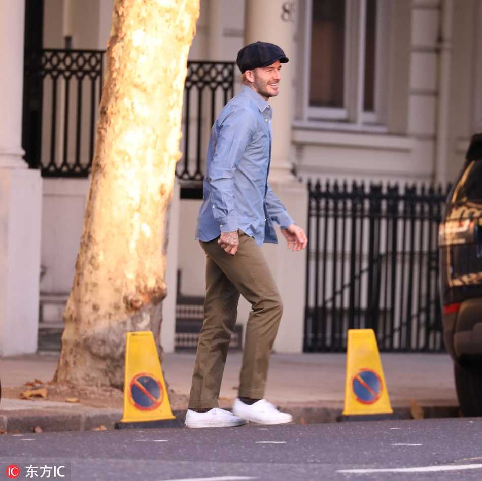 贝克汉姆漫步于伦敦老街，身穿剪裁考究的休闲外套，脸上洋溢着的亲切笑容与身后古典建筑相映成趣，尽显英伦绅士的儒雅风度。