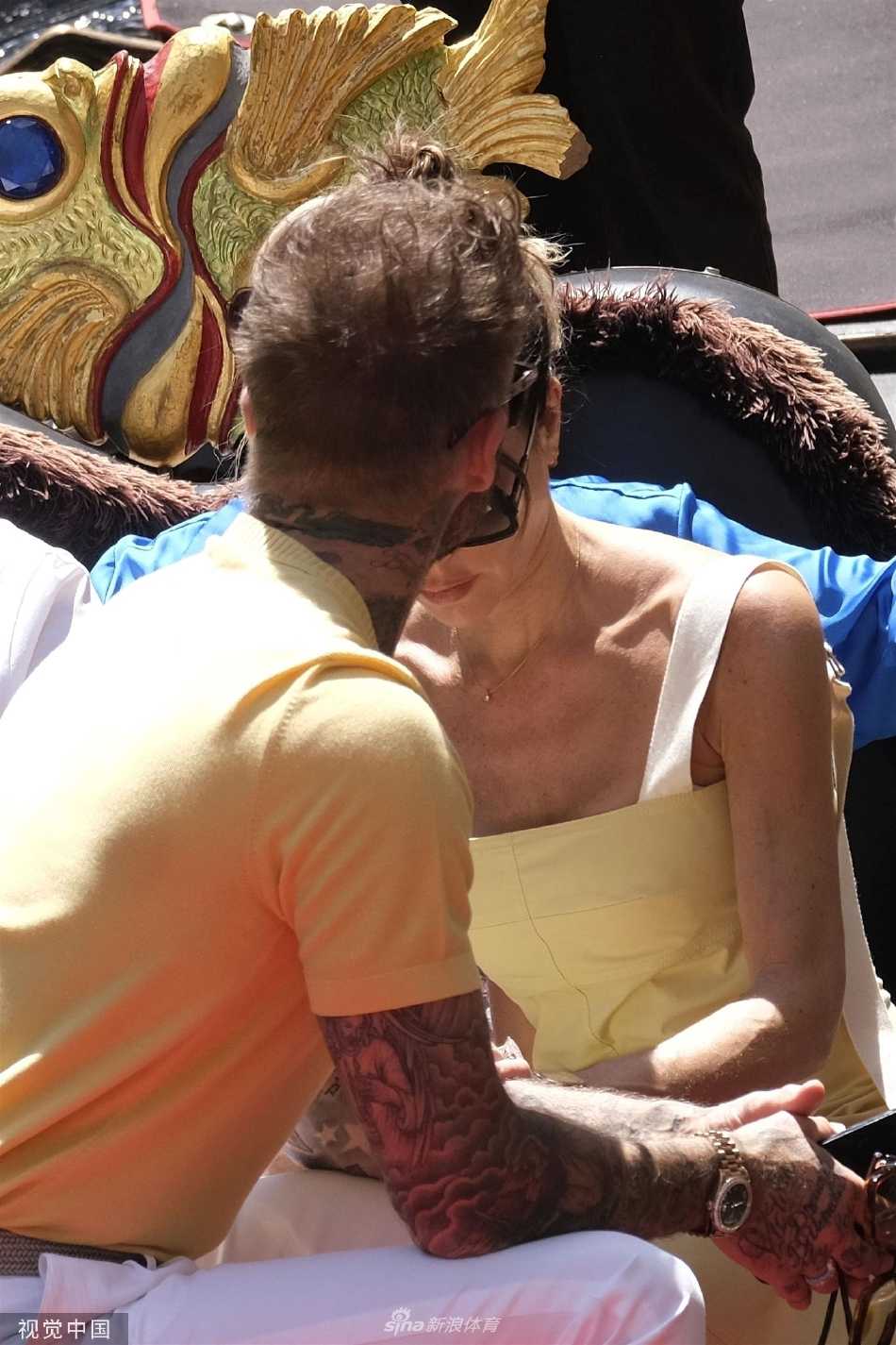 维多利亚侧身坐在船边，展示其连衣裙背后的精致镂空设计，时尚感十足。