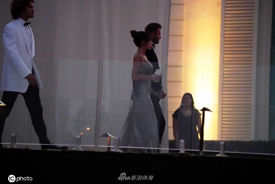 夜幕降临，庄园内灯火璀璨，贝克汉姆夫妇在柔和的灯光下与其他嘉宾合影，笑容灿烂，共同分享着这份家族喜悦。