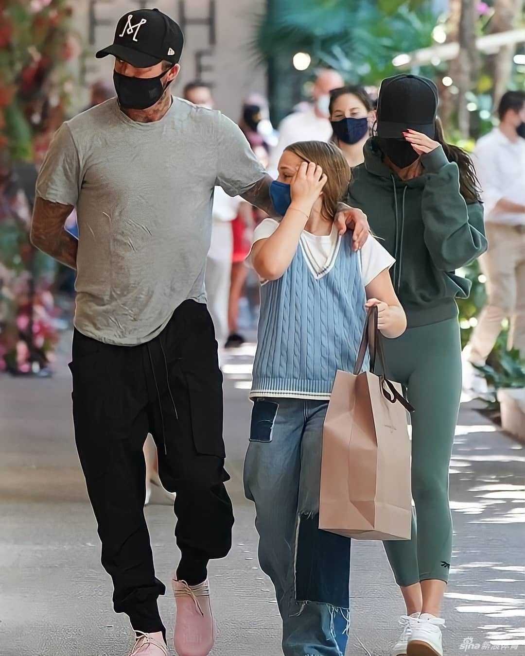 贝克汉姆一家在迈阿密的高档购物区漫步，画面中贝克汉姆的灰色T恤与粉色运动鞋搭配得恰到好处，他紧跟在女儿身后。小七的蓝色叠穿look在阳光下格外醒目，一家人其乐融融的氛围令人羡慕。