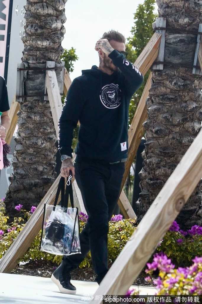 在另一张照片中，贝克汉姆驻足于一片充满热带风情的绿植墙前，阳光透过树叶在他的黑色卫衣上洒下斑驳光影。他双手轻握垂于身前，仿佛正在街边小憩，即便隔着深色镜片，也能感受到那份沉稳自信的明星气场，与周围环境构成一幅和谐又醒目的画面。
